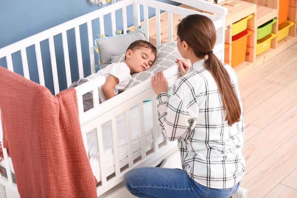 Mãe olhando o bebê dormir no berço