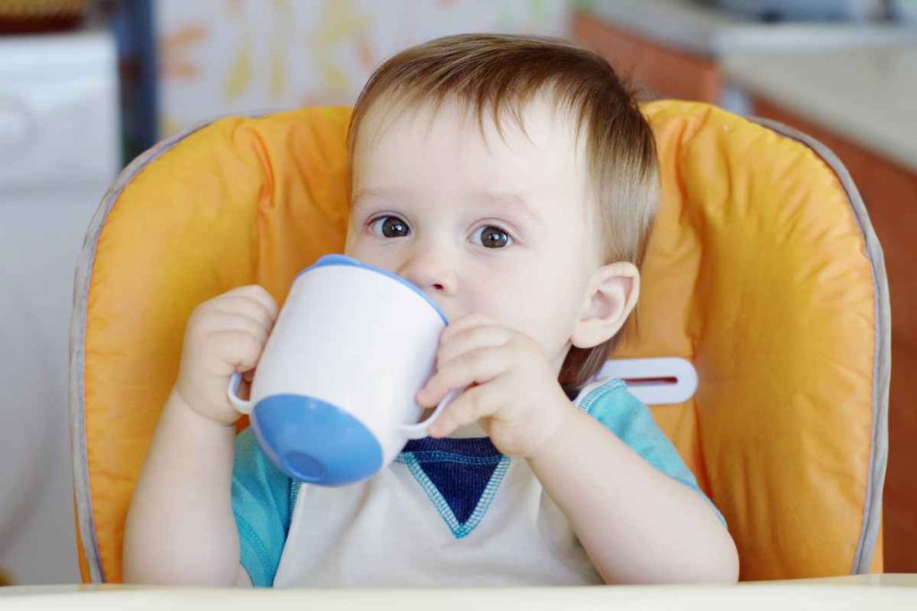 Bebê bebendo água no copo de transição