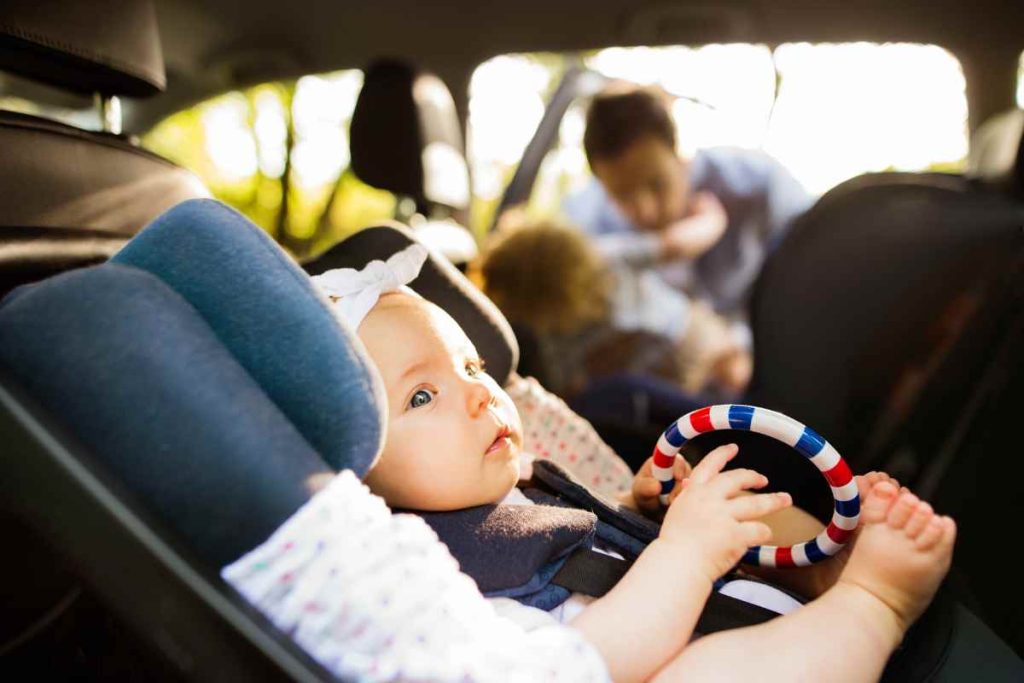 bebê com seu brinquedo na cadeirinha para auto