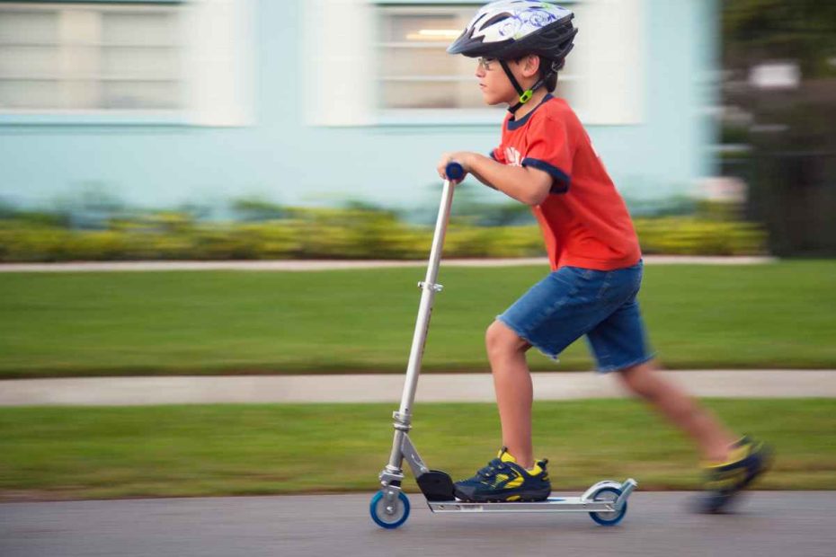 criança andando de patinete com capacete de segurança