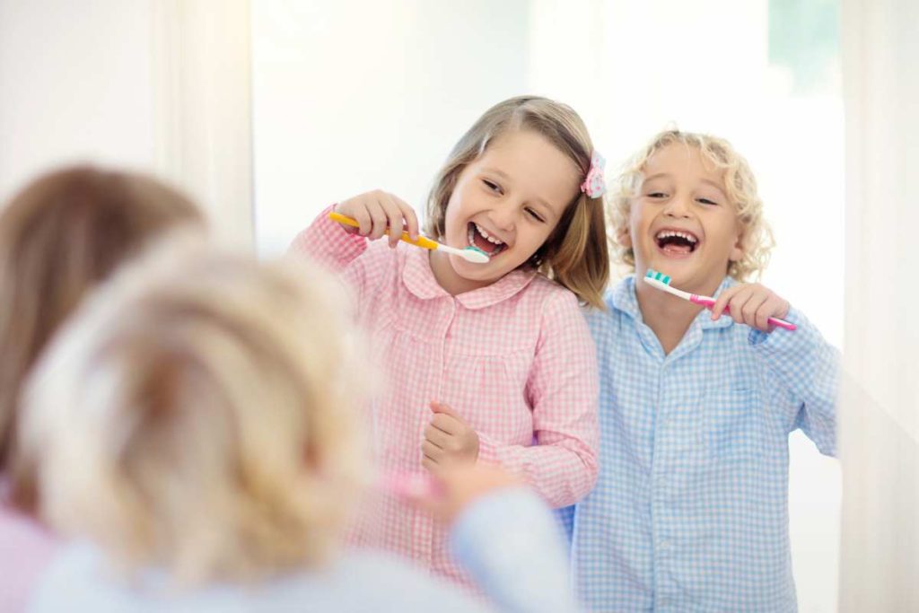 Crianças escovando os dentes com pasta de dente infantil