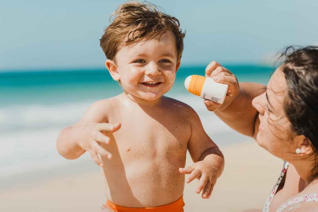 Mãe passando o melhor protetor solar no filho
